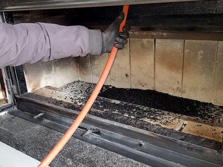 Ramonage d’un insert : la tige rotative remonte dans le conduit depuis le foyer